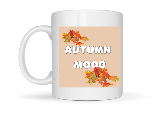 “White ceramic mug with a cartoon cat in a scarf holding a warm drink on one side, and ‘AUTUMN MOOD’ text with fall leaves on the other.”